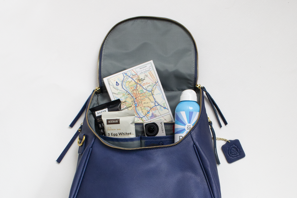 Blue Backpack with map, sunscreen, granola bars, and gopro sticking out