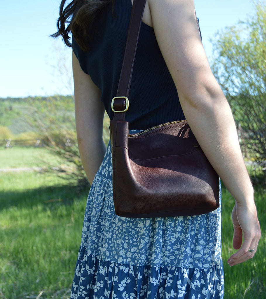 Woman posing with brown leather Osgoode Marley bag.